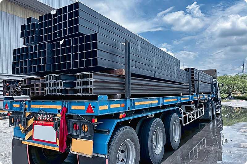 Flatbed semi trailer carrying secured steel materials for construction supply